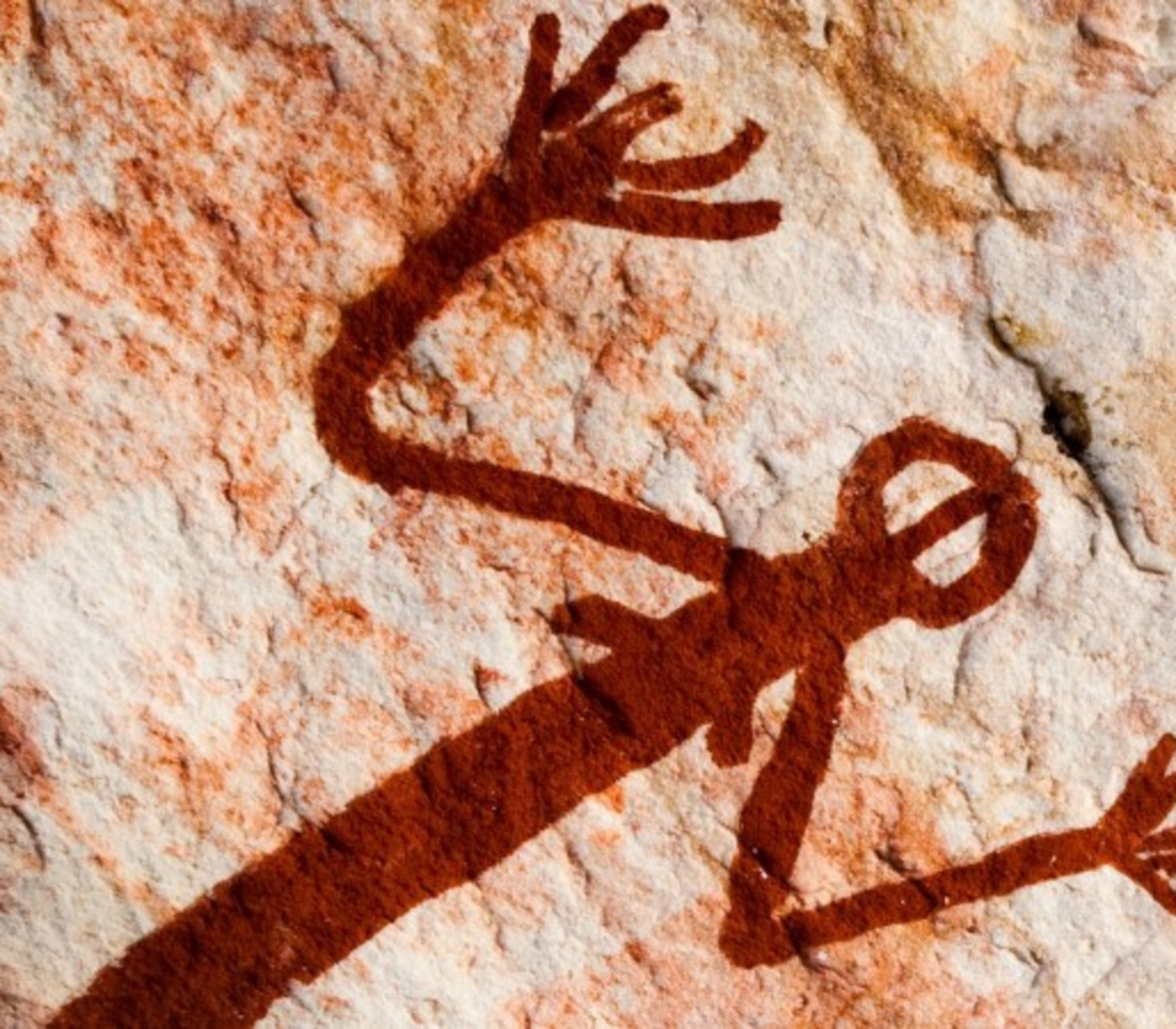 Close-up of traditional Indigenous Australian rock paintings in red ochre on a textured sandstone wall in Kakadu.