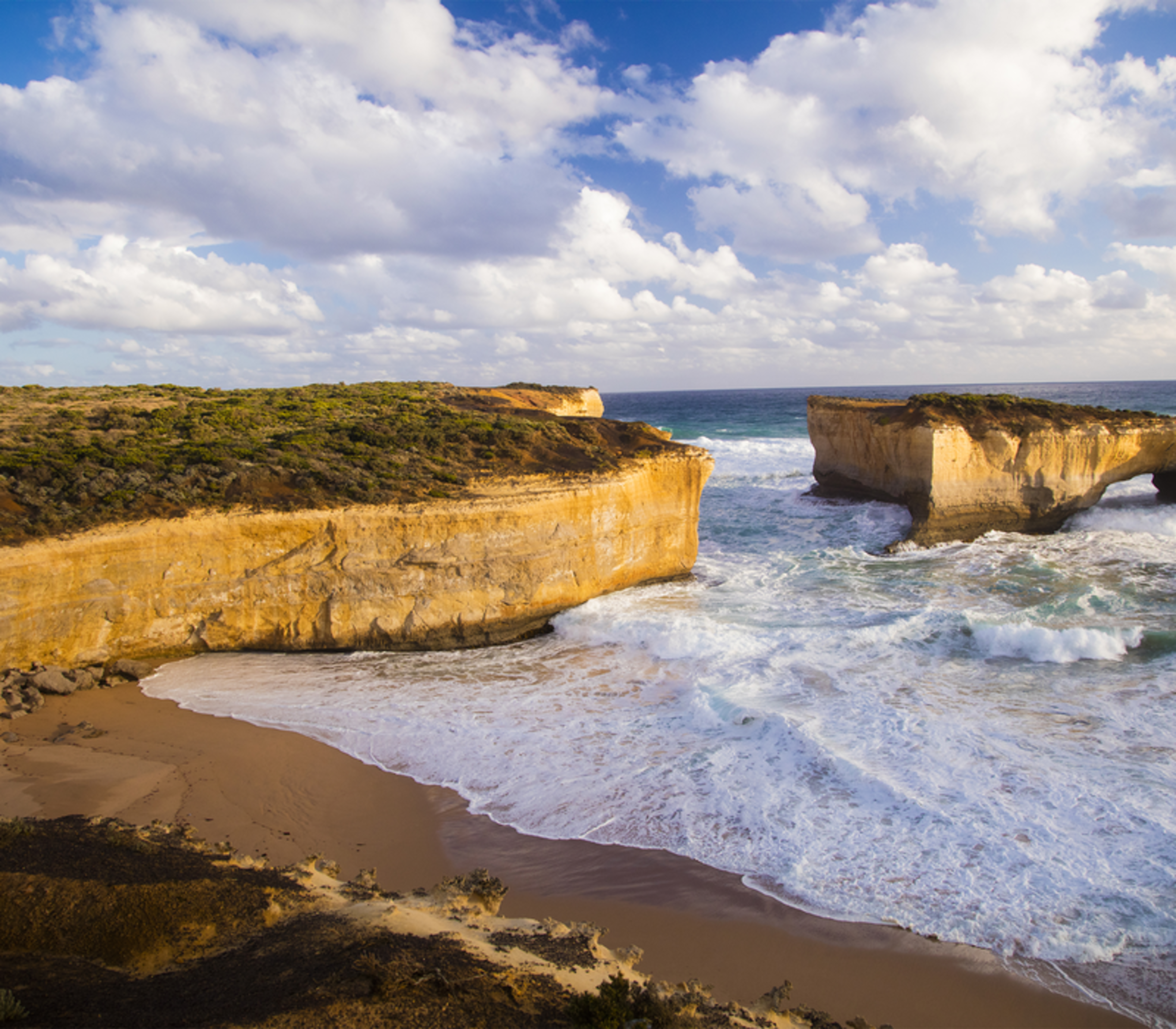 Scenic coastal view of the London Arch rock formation and a secluded beach on the Great Ocean Road in Victoria.