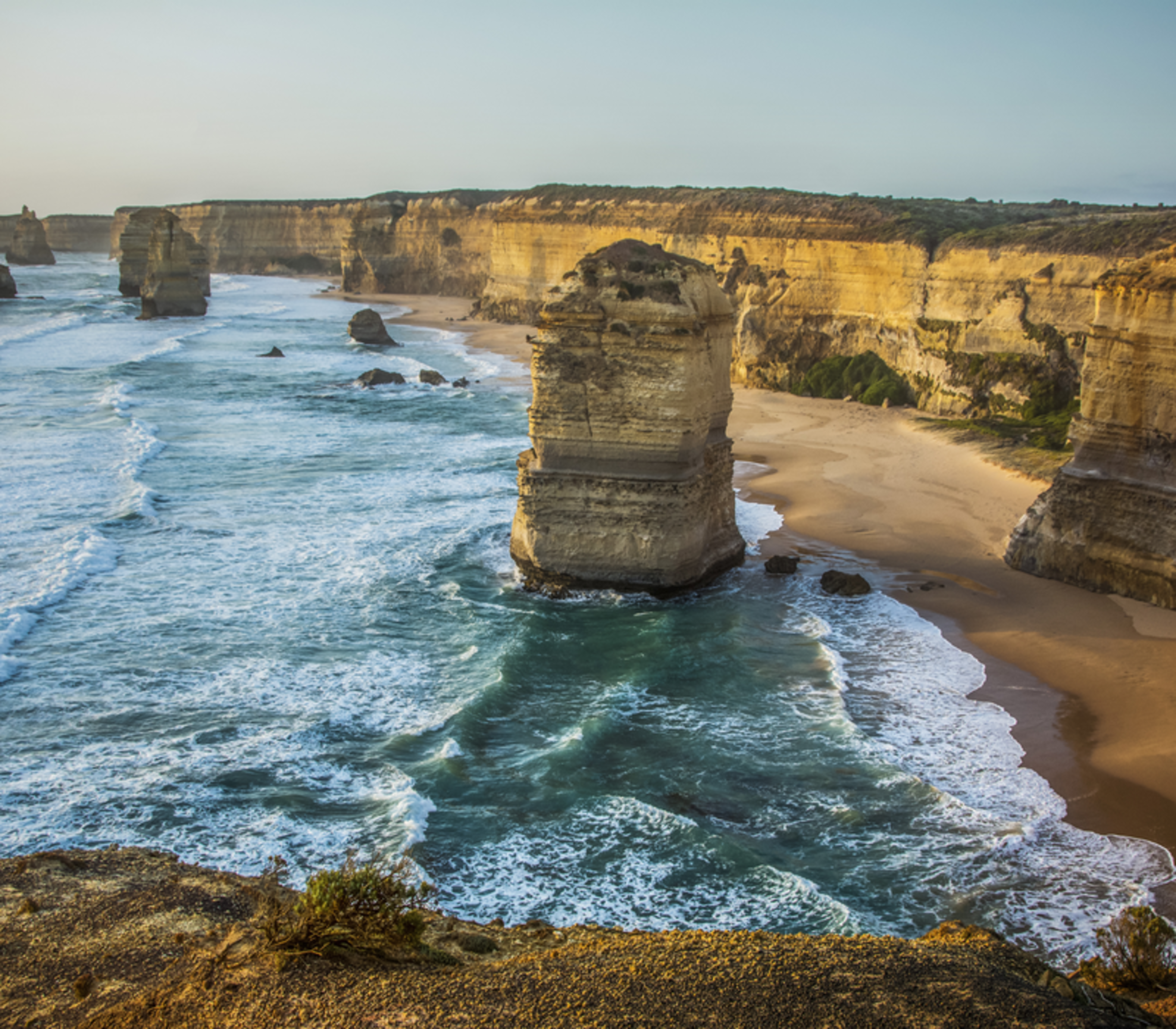 Scenic view of limestone rock stacks in the ocean along a high cliff coastline.