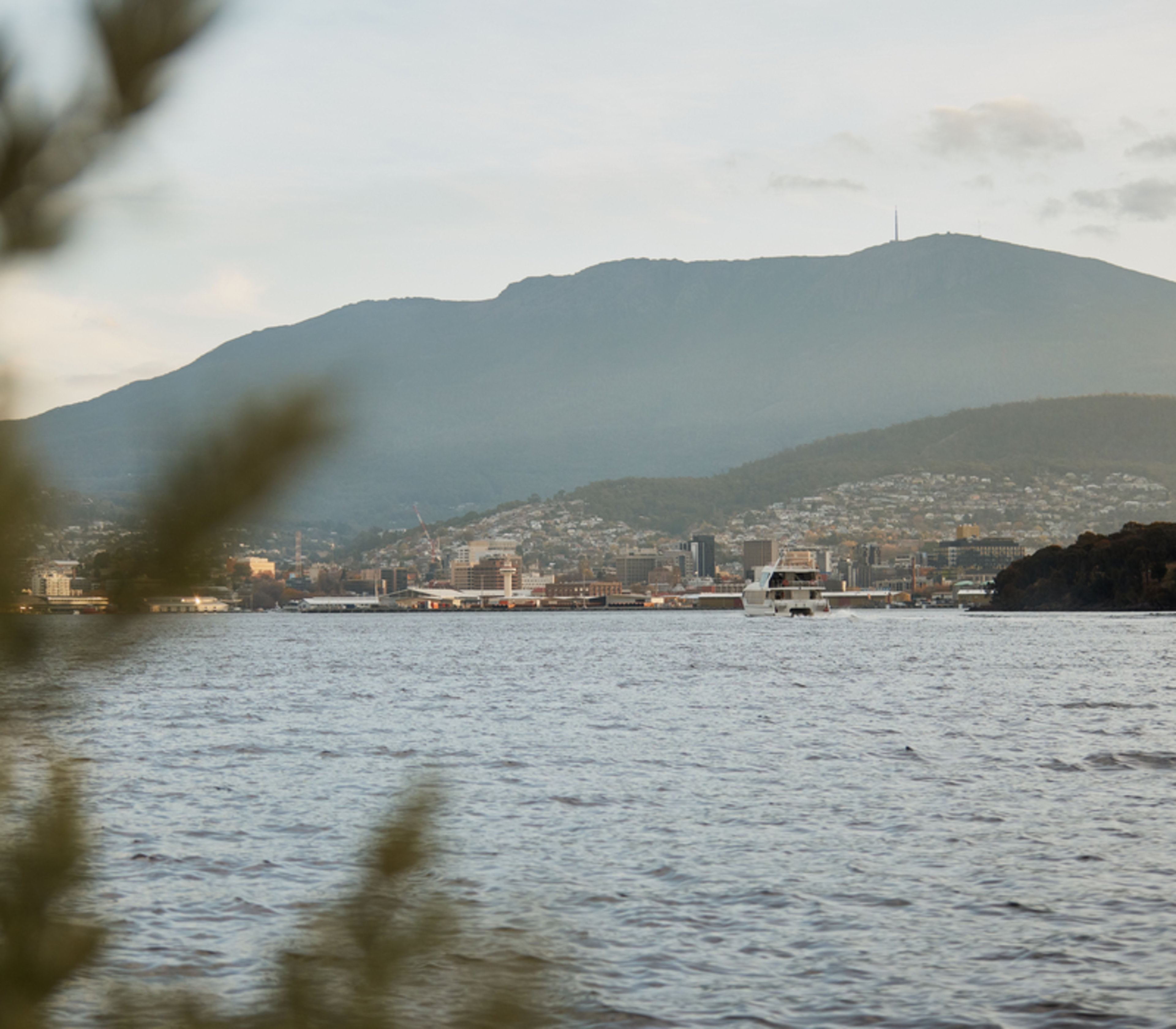 The Hobart city skyline and Mount Wellington seen across the water at dusk.