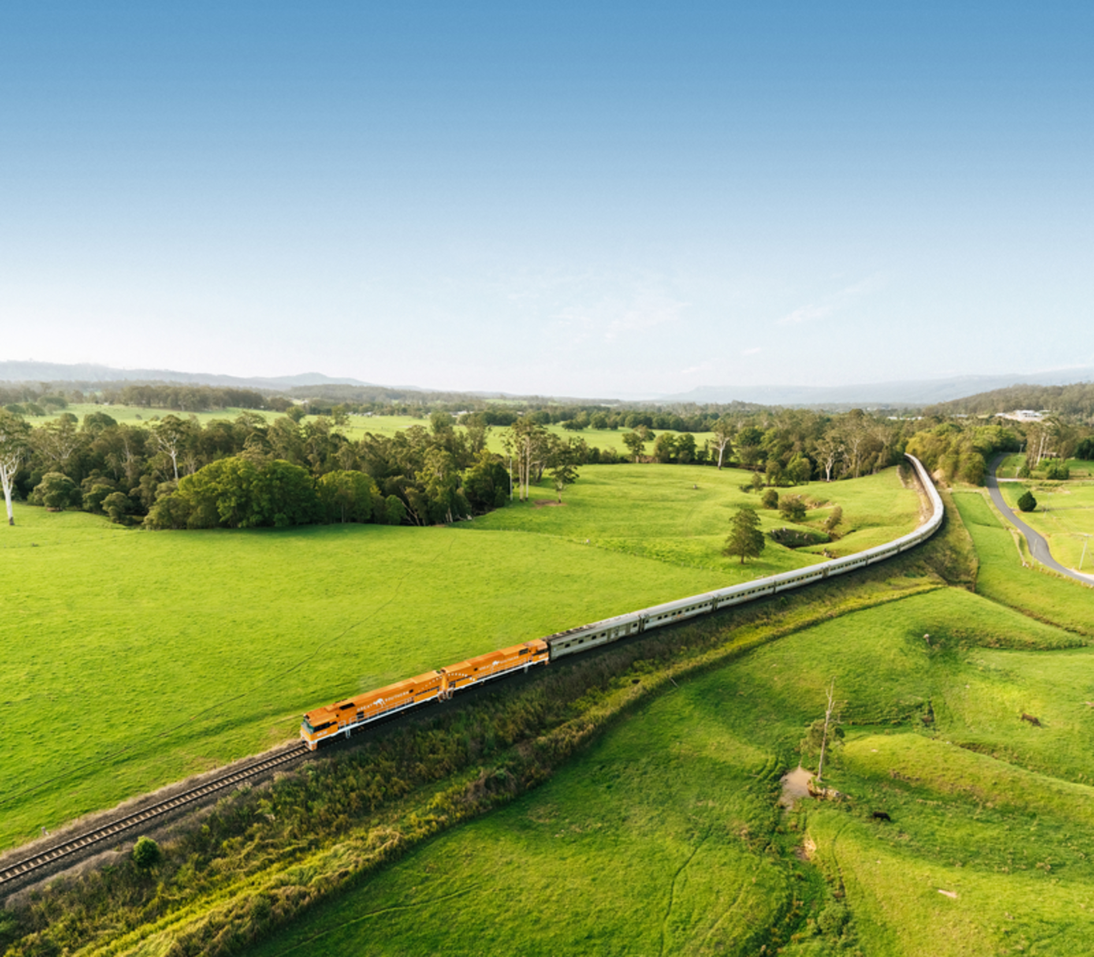 The Great Southern passenger train traveling through lush green meadows in rural New South Wales.