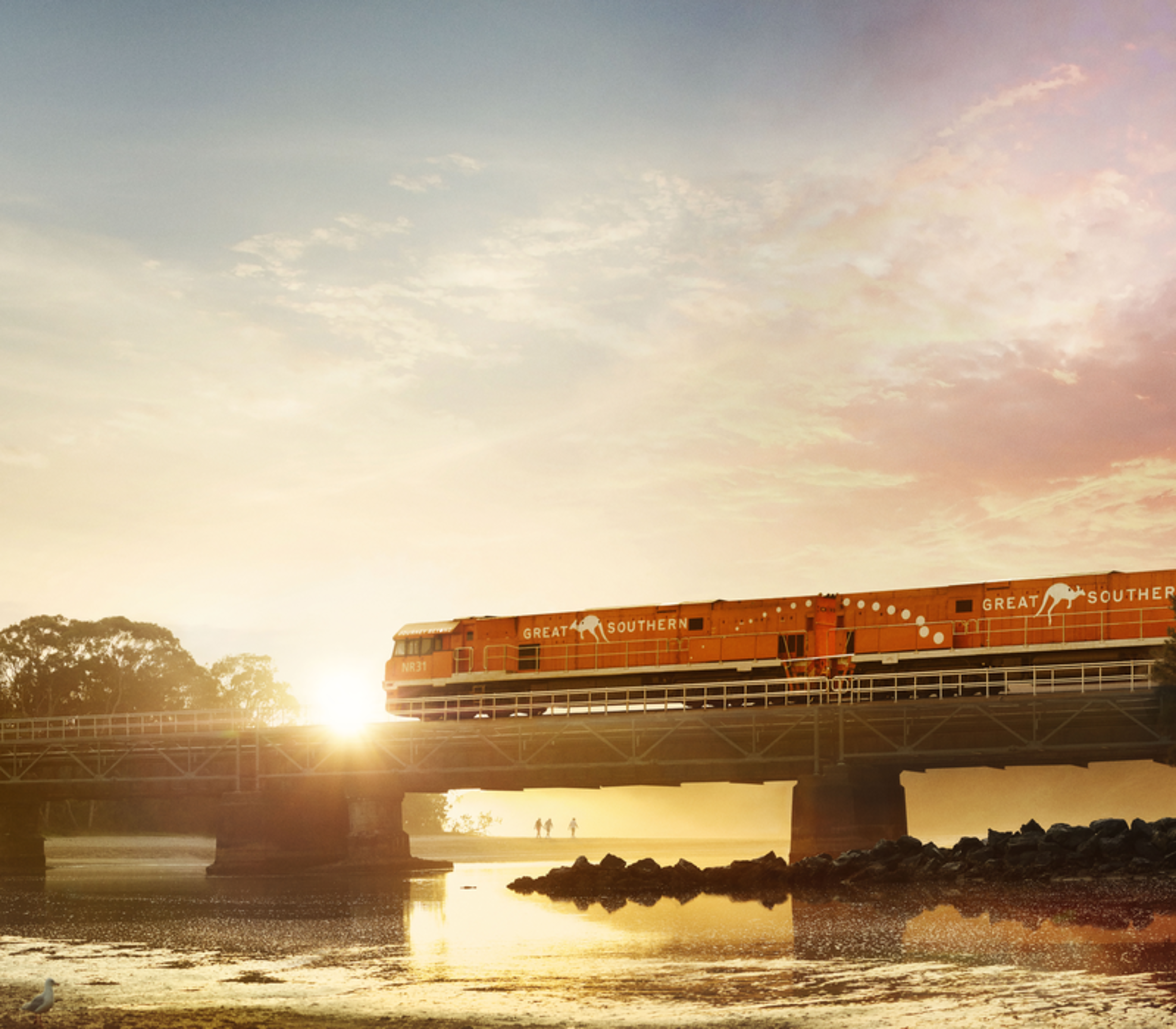 A train on a bridge at sunrise with a vibrant pink and orange sky.
