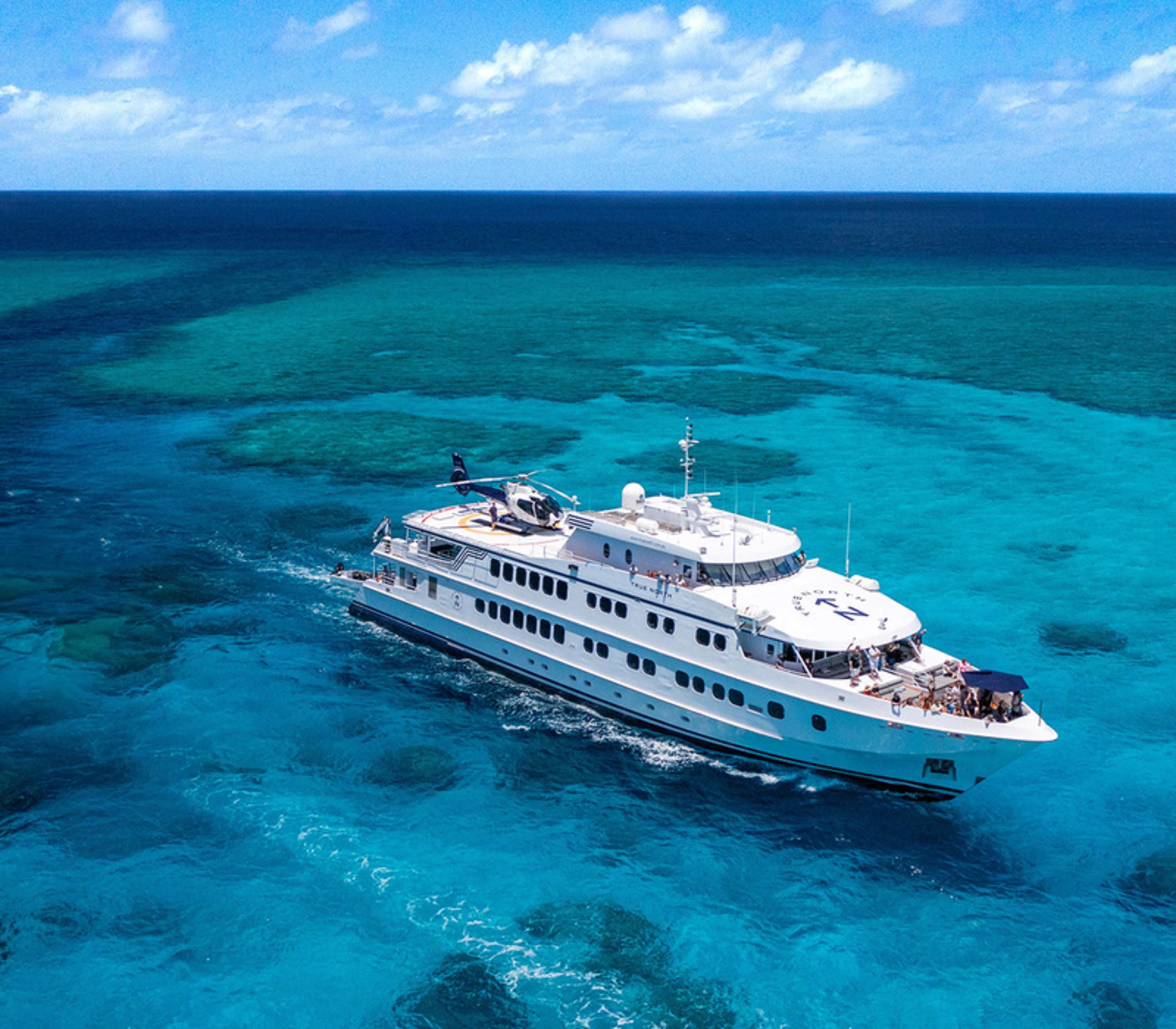 The 50-metre flagship vessel True North navigates the crystal-clear turquoise waters of the Great Barrier Reef. 